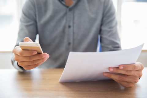 Businessman reading document and texting message