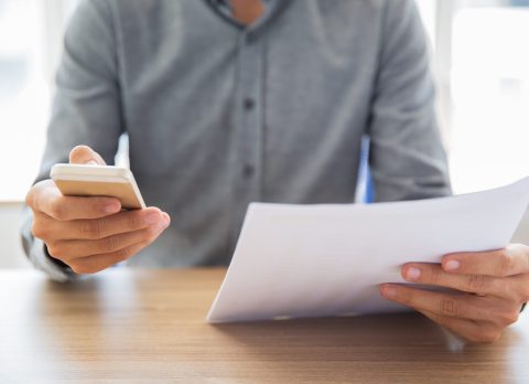 Businessman reading document and texting message